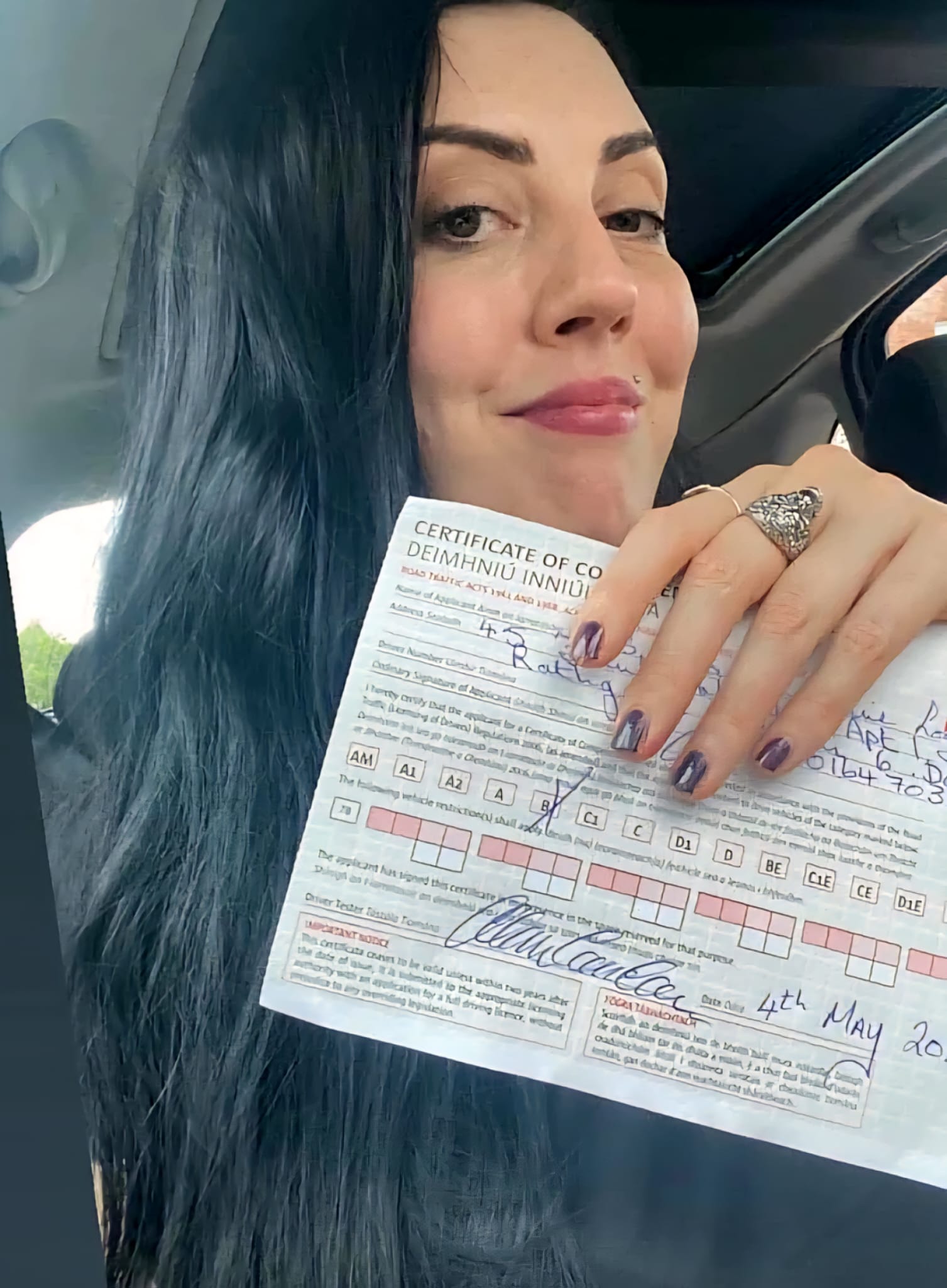 Student holding her Certificate of Competency in the car