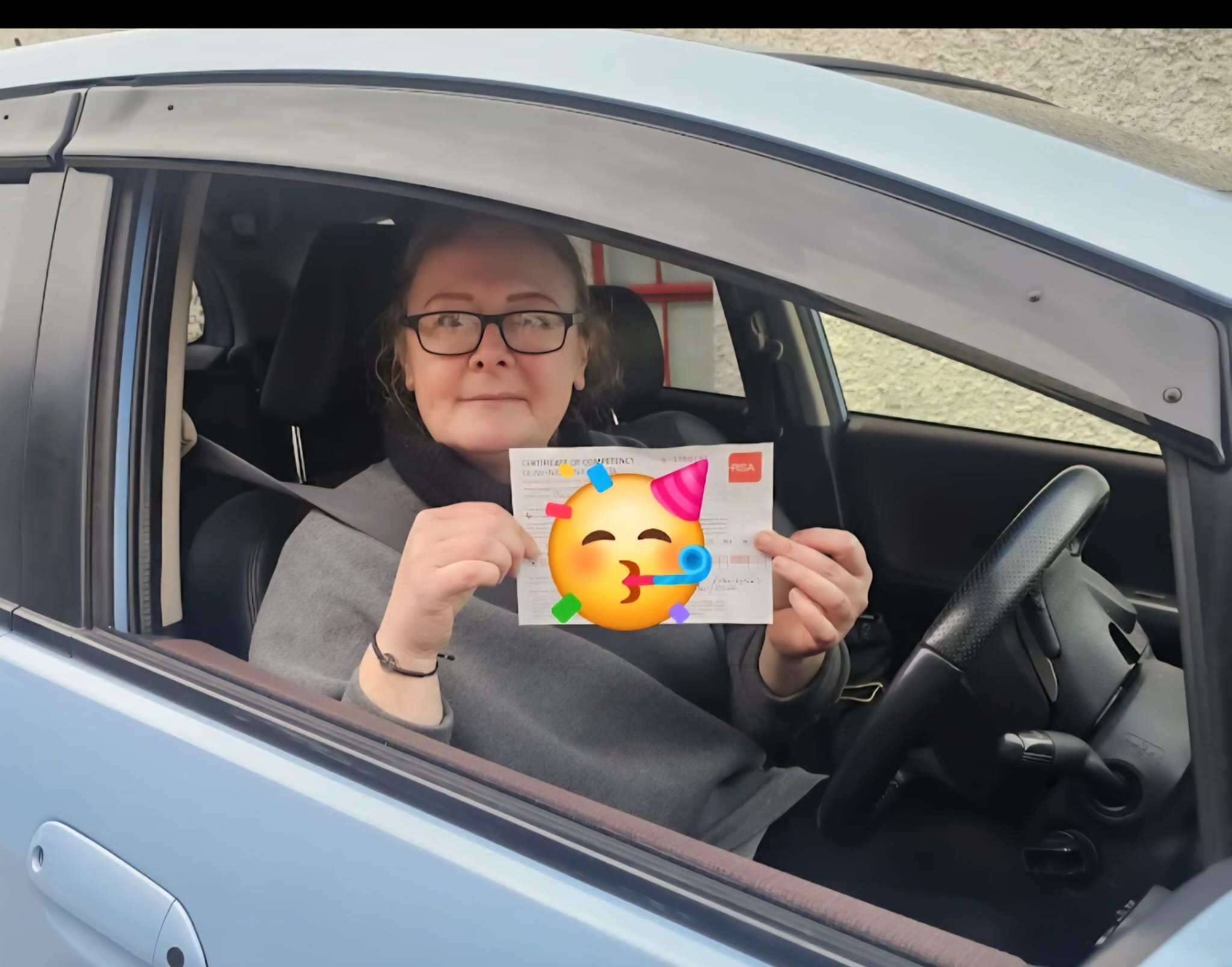 Student holding her pass certificate from the driver's seat